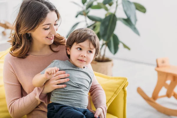 Lycklig Mamma Kramar Bedårande Son Medan Sitter Soffan Hemma — Stockfoto