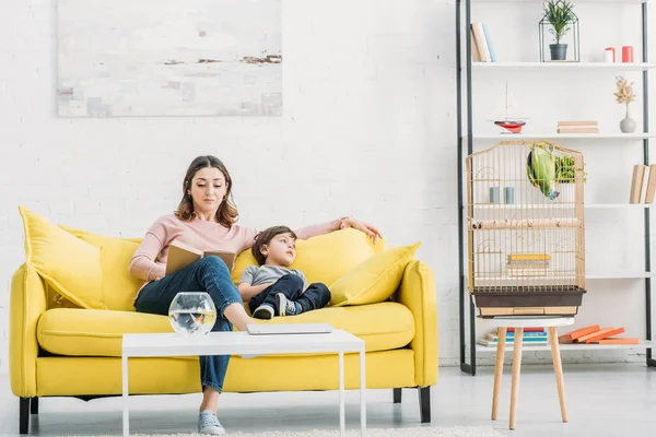 Attraktive Frau Mit Entzückendem Sohn Auf Gelbem Sofa Geräumigen Wohnzimmer — Stockfoto