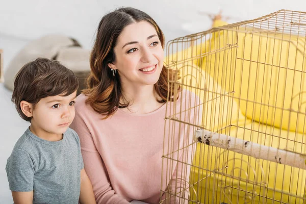 Happy Mother Adorable Attentive Son Looking Bird Cage Home — Stock Photo, Image