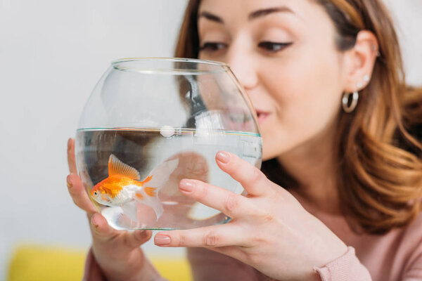 beautiful young woman holding fish bowl with bright golden fish