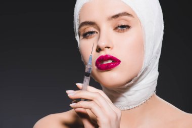 gri üzerinde izole yüz yakın bandajlı kafa tutan şırınga ile genç kadın 