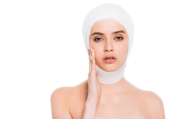 白い上に分離されたプラスチック手術の後に包帯の頭に触れる顔をした裸の少女 — ストック写真