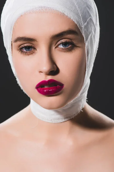 close up of beautiful girl with bandaged head looking at camera isolated on grey