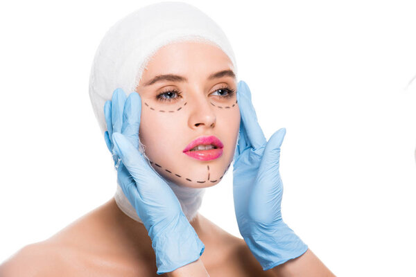 cropped view of plastic surgeon in latex gloves touching woman with marks on face isolated on white 