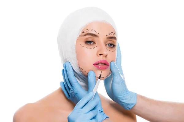 穿着蓝色乳胶手套的整形外科医生的裁剪视图与手术刀附近的妇女的脸与标记查出在白色 — 图库照片
