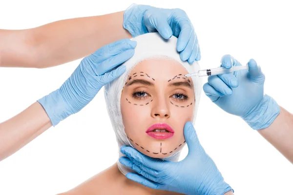 穿着蓝色乳胶手套的整形外科医生的裁剪视图 用注射器靠近妇女的脸 在白色上查出痕迹 — 图库照片