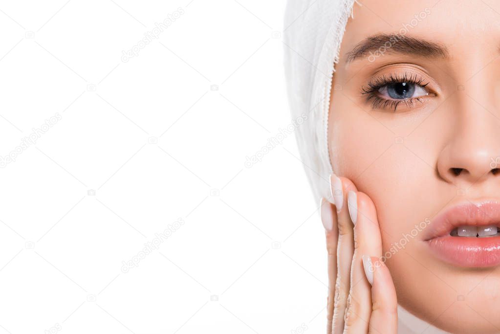 cropped view of young woman with bandaged head touching face after plastic surgery isolated on white 