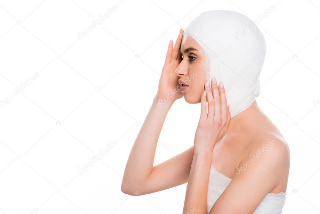 girl with bandaged head touching face after plastic surgery isolated on white 