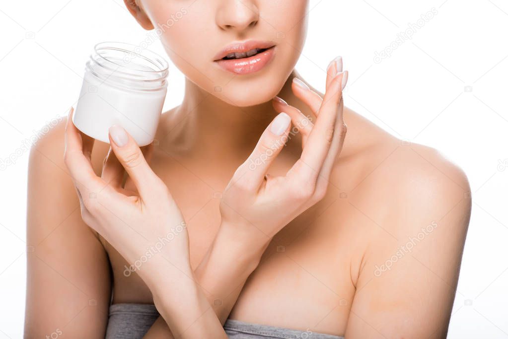 cropped view of woman holding container while applying cosmetic cream isolated on white 