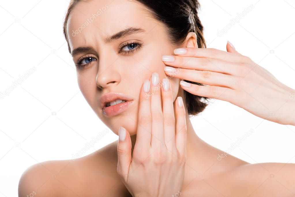 sad brunette woman touching face and looking at camera isolated on white 