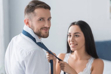 yakışıklı adam seçici odak mutlu kadın bağlama kravat yakınında duran 