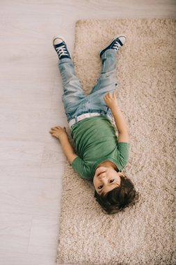 yeşil t-shirt halı üzerinde yatan meraklı küçük çocuğun havai görünümü