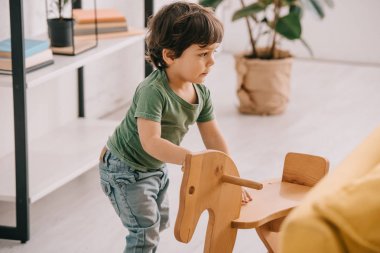 ahşap sallanan at ile oynayan yeşil t-shirt çocuk