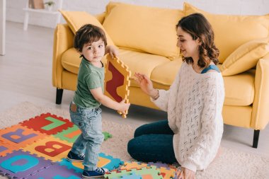 Alfabe bulmaca mat ile oynayan gülümseyen anne ve çocuk