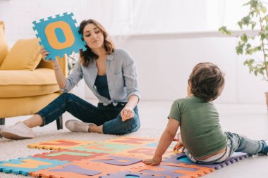 Alfabe bulmaca mat ile oynayan gülümseyen anne ve çocuk