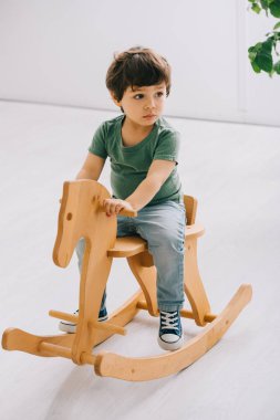 oturma odasında ahşap sallanan at üzerinde oturan çocuk
