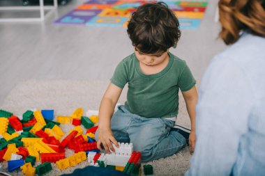 oturma odasında halı üzerinde lego ile oynayan anne ve oğlu kırpılmış görünümü