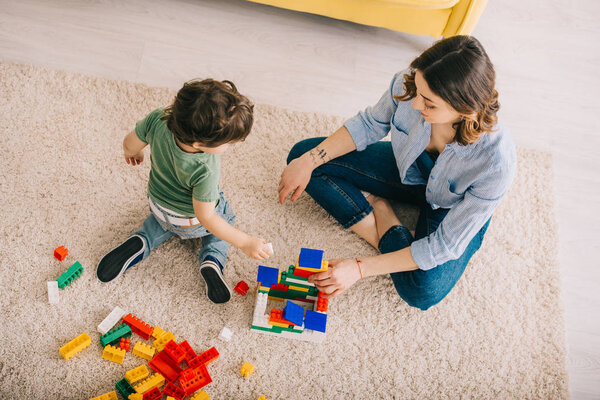 High angle view of mom and son playing with toy blocks in living room