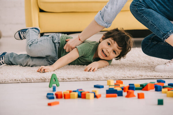 Cropped view of mother playing with son on carpet