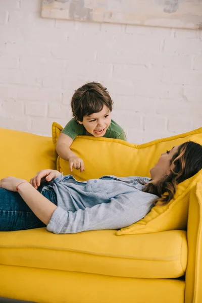 Skrikande Pojke Stående Nära Trött Mamma Liggande Gul Soffa Vardagsrummet — Stockfoto