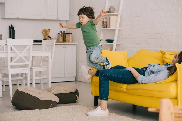 Niño Divertirse Mientras Cansado Madre Acostado Sofá — Foto de Stock