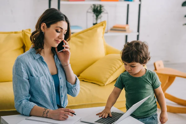 Kid Touching Laptop Keyboard While Mother Talking Smartphone — Stock Photo, Image