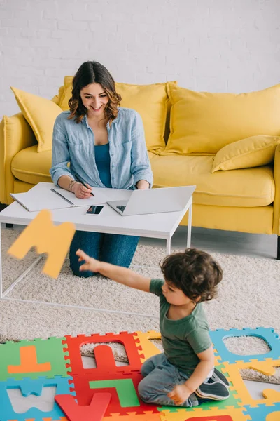 Lachende Moeder Kijkt Naar Zoon Spelen Met Puzzel Mat — Stockfoto