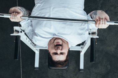 Spor salonunda barbell ile Kilolu dövmeli adam eğitim üst görünümü