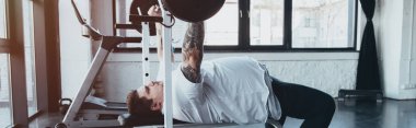 Spor salonunda barbell ile Kilolu dövmeli adam eğitim panoramik çekim