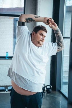 spor merkezinde uzanan beyaz t-shirt kilolu dövmeli adam