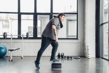 spor merkezinde adım platformunda havlu egzersiz ile kilolu adam