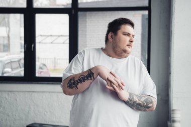 spor salonunda beyaz t-shirt germe parmakları kilolu dövmeli adam