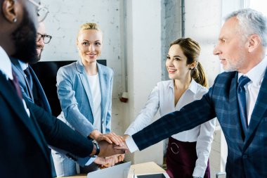 neşeli çok kültürlü işadamları ve iş kadınlarının seçici odak birlikte el koyarak 