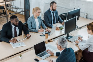 gadget'lar yakınında ofiste çalışan çok kültürlü işadamları ve iş kadınlarının genel bakış 