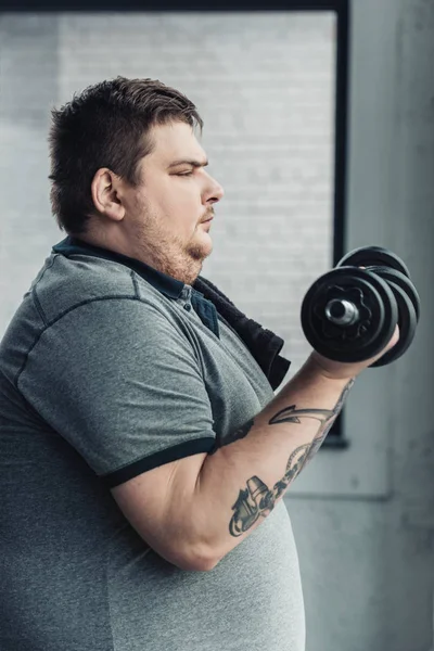 Pemandangan Samping Dari Pria Bertato Obese Berolahraga Dengan Dumbbells Pusat — Stok Foto