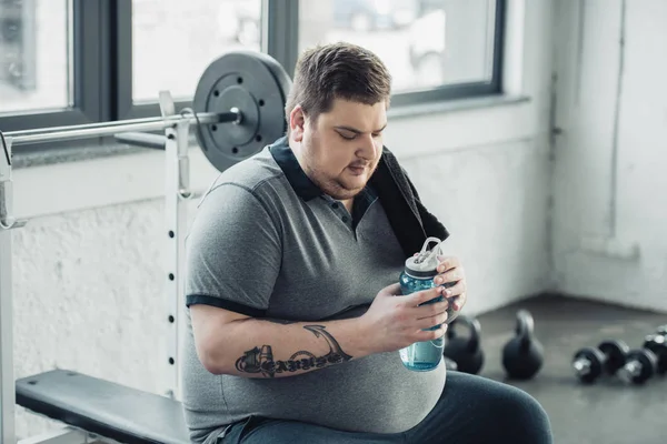 Kilolu Dövmeli Adam Bankta Oturan Spor Salonunda Spor Şişesi Tutarak — Stok fotoğraf