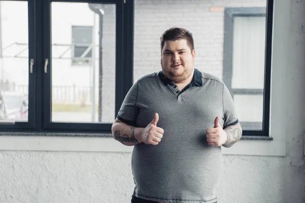 Overgewicht Getatoeëerde Man Grijs Shirt Kijkend Naar Camera Het Tonen — Stockfoto