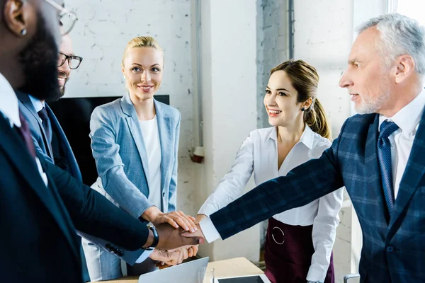 neşeli çok kültürlü işadamları ve iş kadınlarının seçici odak birlikte el koyarak 