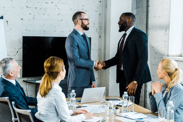 Hombres Negocios Multiculturales Estrechando Mano Cerca Colegas Sala Conferencias — Foto de Stock