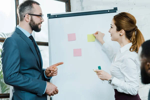 Businessman Glasses Pointing Finger Businesswoman Putting Sticky Notes White Board — Stock Photo, Image