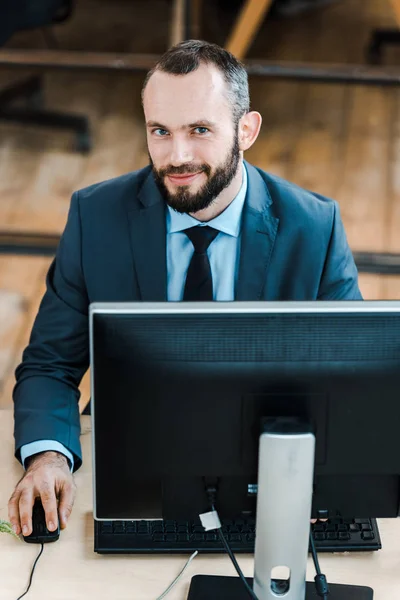 Vrolijke Baard Zakenman Kijkend Naar Camera Buurt Van Computer Monitor — Stockfoto