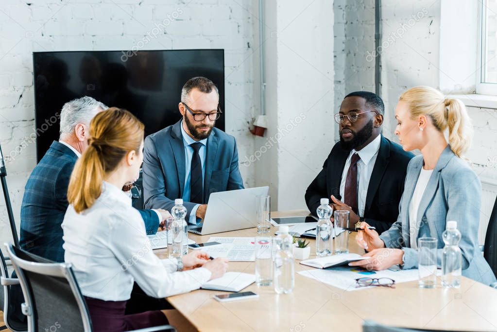 multicultural businessmen having conversation with businesswomen in conference room 