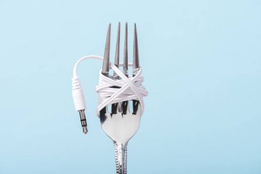 kopyalama alanı ile mavi izole metal çatal üzerine sarılmış kulaklıküst görünümü, müzik konsepti