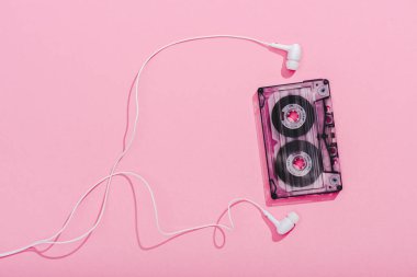 top view of vintage audio cassette with earphones on pink, music concept clipart