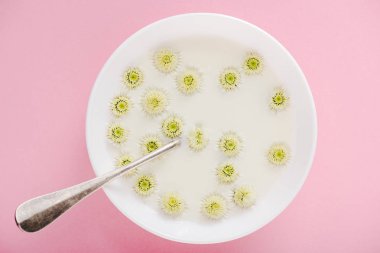 top view of spoon and chrysanthemum flowers in bowl with porridge on pink clipart