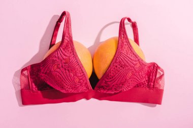 top view of bra with two oranges on pink, breasts concept clipart