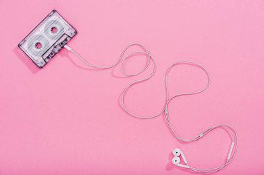top view of vintage audio cassette with earphones on pink, music concept clipart