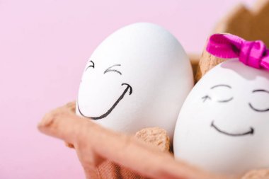 close up of eggs with happy face expressions in egg carton Isolated On pink clipart