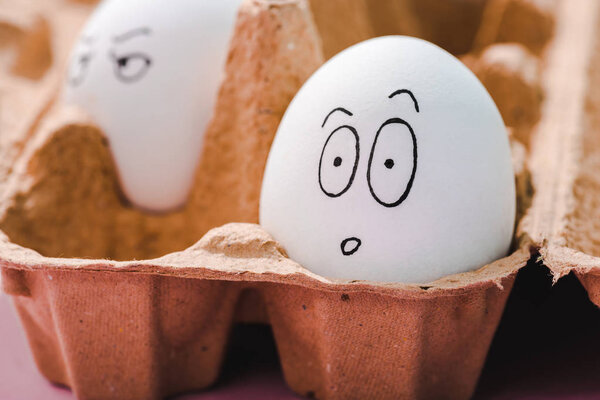 selective focus of egg with surprised face expression in egg carton