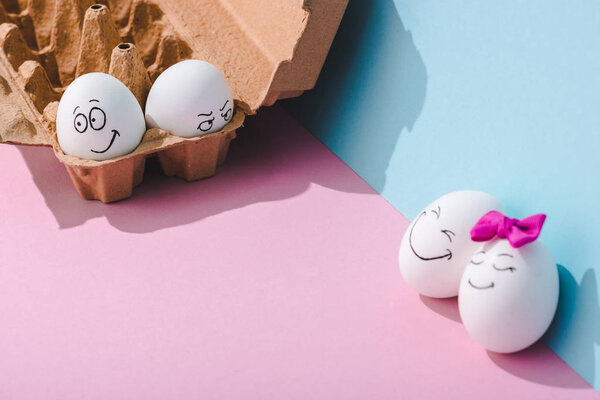 eggs with smiling and angry face expressions on blue and pink with copy space